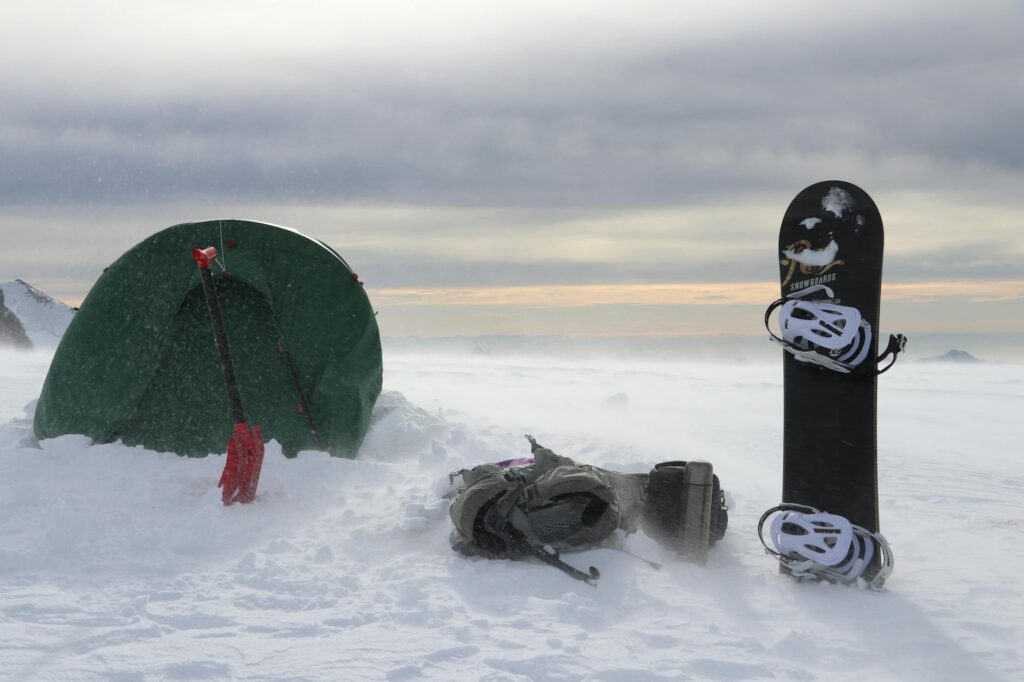 tent shovel snowboard and backpack in snow